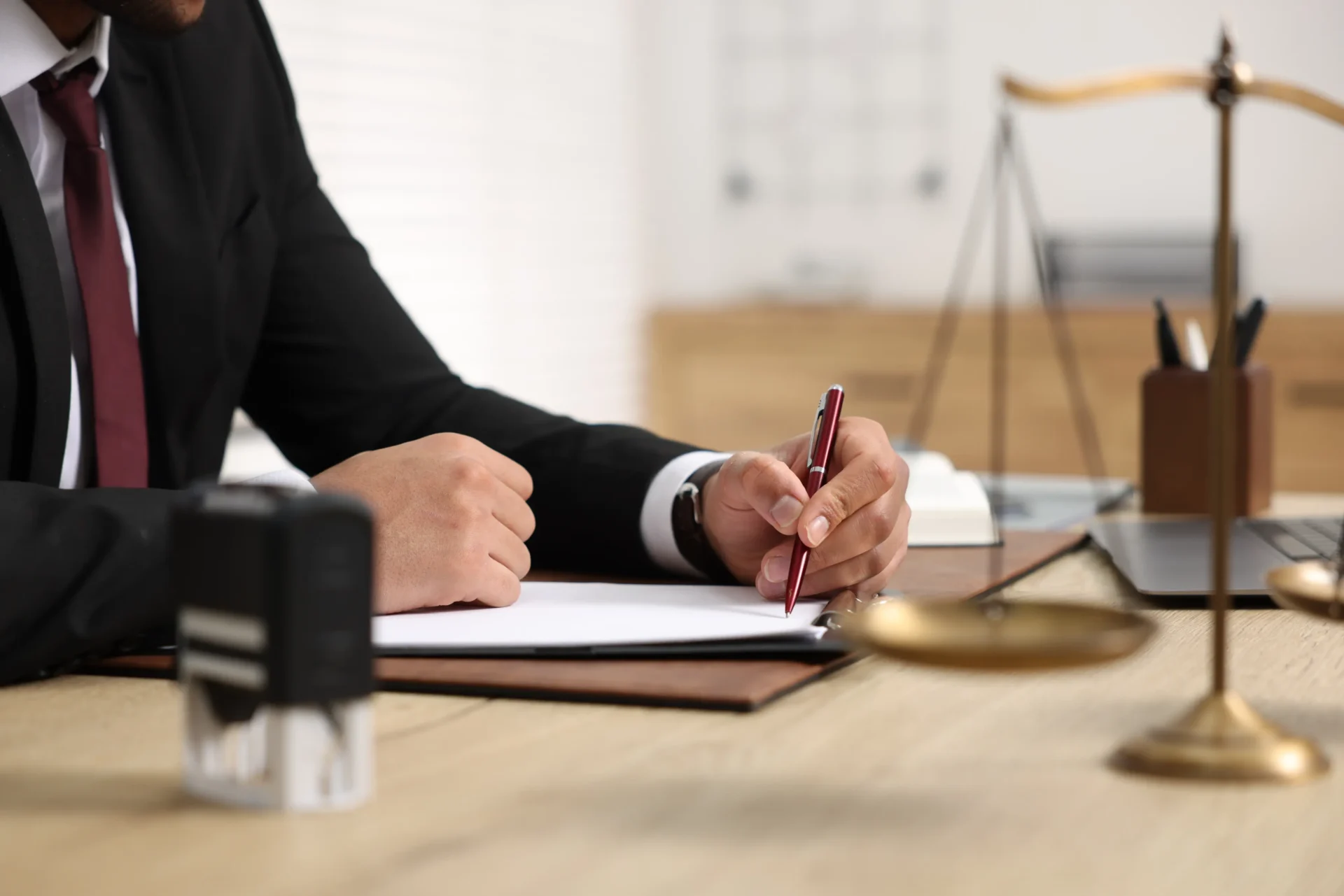 Lawyer signing legal document at desk.